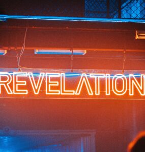 a neon sign reads revelation in red