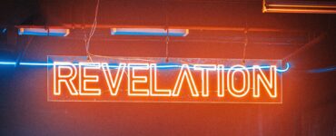 a neon sign reads revelation in red